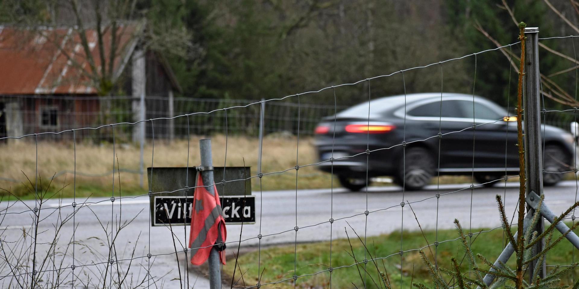 Här i Lindhult vill Trafikverket anlägga en av sina &quot;viltövergångar&quot; genom viltstängslet. Platsen är olycksdrabbad, vilket skylten och reflexvästen som gårdsägaren har till hands vittnar om.